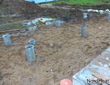 Цементная труба 2-х метровой длины устанавливается в отверстие и обсыпается щемнем. Далее площадка под террасу каркасного дома отсыпается песком